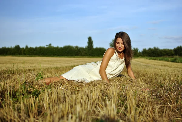 Nice girl in national dress sitting on a field in rural areas — Stock Photo, Image