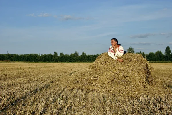 干し草の山の上に横たわる、ロシアの伝統的な衣装の女の子 — ストック写真