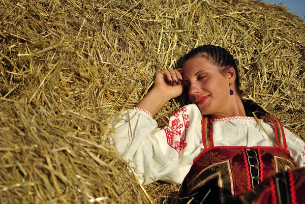 Fille en costume traditionnel russe reposant sur une meule de foin — Photo