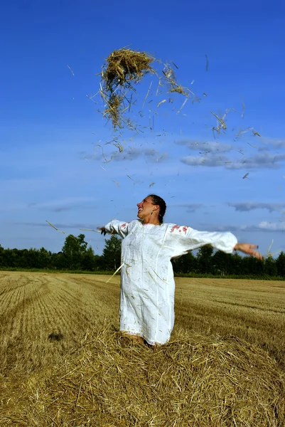Flicka i traditionell rysk dräkt slänga höet på en höstack — Stockfoto