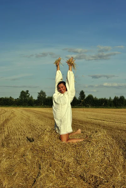 Flicka i traditionell rysk dräkt som sitter på en höstack — Stockfoto