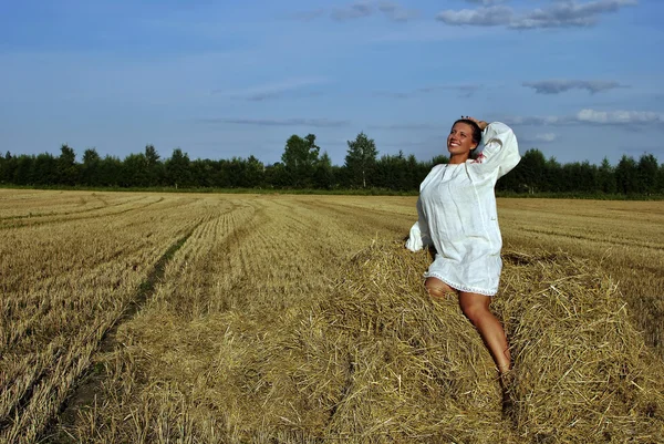 전통적인 러시아 의상 건초 더미에 앉아서 웃 고 있는 여자 — 스톡 사진