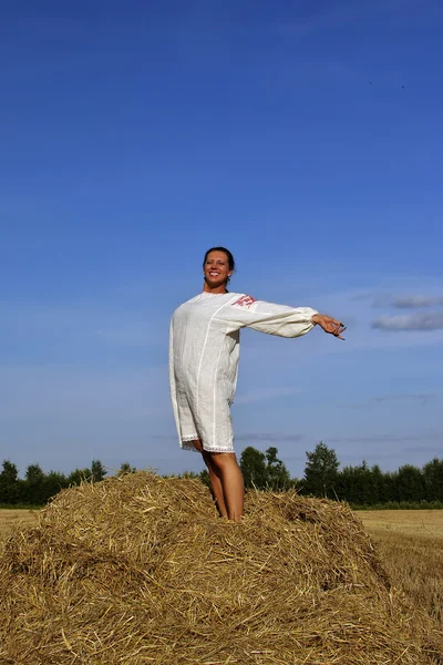 在传统的俄罗斯服装站在干草堆上的女孩 — 图库照片