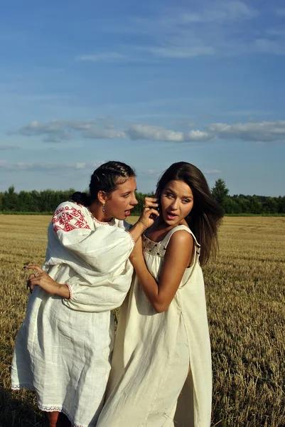 Two girls in a rural clothing talking on the phone — Stock Photo, Image