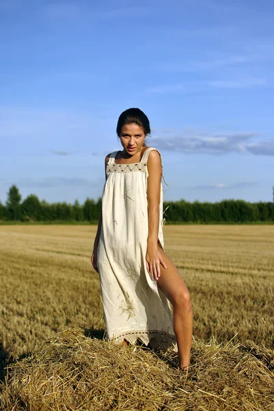 Meisje in een landelijke kleding staande op de hooiberg — Stockfoto