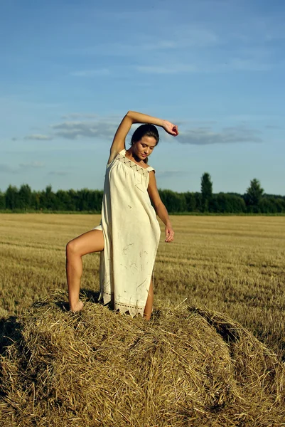 Menina em uma roupa rural em pé no palheiro — Fotografia de Stock