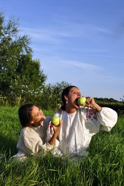 Δύο κορίτσια στην παραδοσιακή φορεσιά τρώνε μήλα — Φωτογραφία Αρχείου