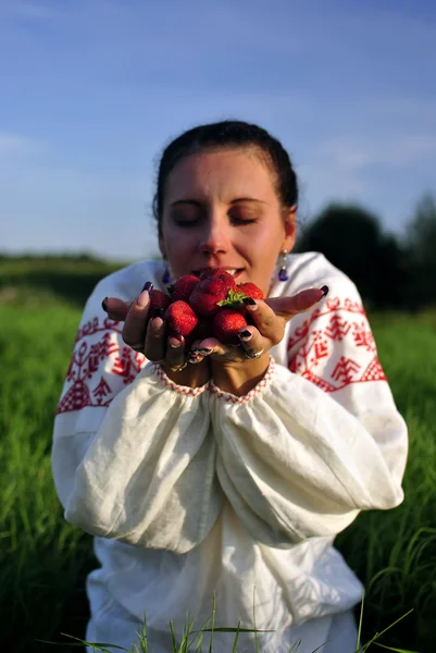 Russian girl in traditional dress holding a strawberry in hand — Stock Photo, Image