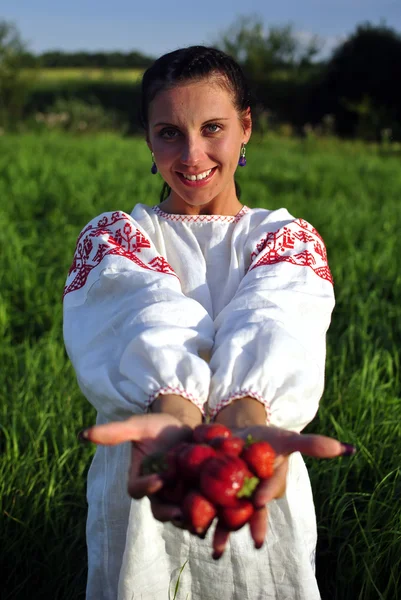 Russian girl in traditional dress holding a strawberry in hand — Stock Photo, Image