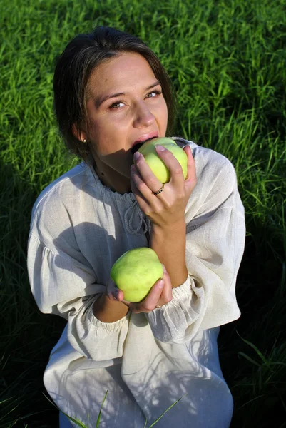 Girl in a linen shirt, eating apples — Stock Photo, Image