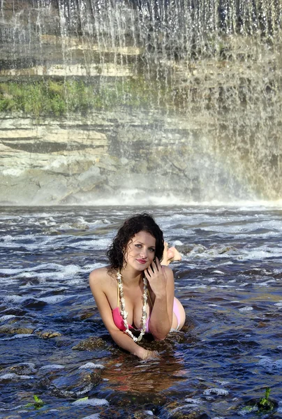 Girl in bikini lying near a waterfall — Stock Photo, Image