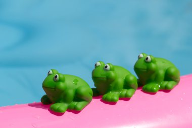 Toy frog on an inflatable pool clipart