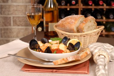 Bowl of seafood soup with wine and rustic bread clipart