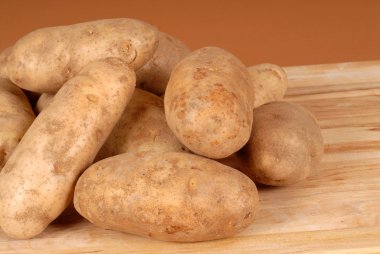 Several russet potatoes piled on a cutting board clipart