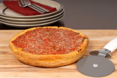 A Chicago style deep dish pizza on a cutting board clipart