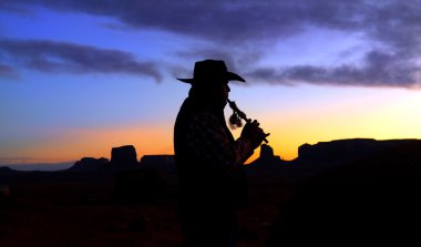 Navajo Native American Indian playing flute at sunrise clipart
