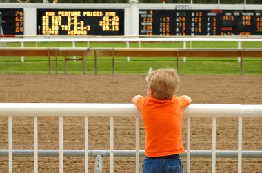 Young boy waiting for horses at race track clipart