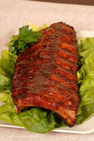 Slab of ribs resting on lettuce — Stock Photo, Image