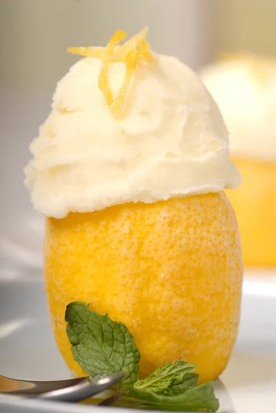 Два лимонных сорбета в замороженной лимонной скорлупе с мятой. — стоковое фото