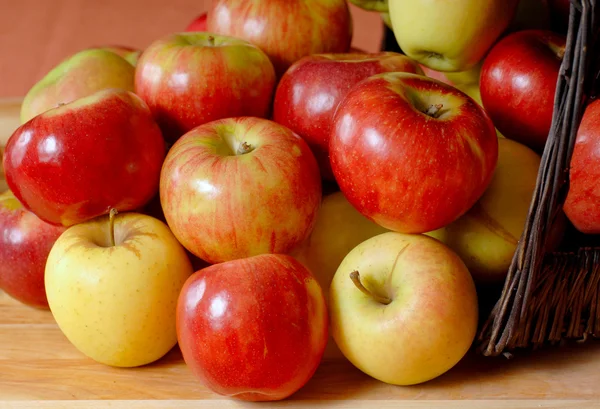 Корзина, полная яблок, переливающихся на стол — стоковое фото