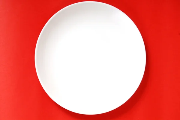 stock image Simple white plate on a red background