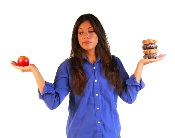 Young woman deciding to eat apple or donuts — Stock Photo, Image