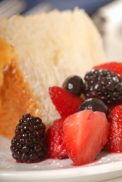 Bit av ängel mat kaka med färsk frukt — Stockfoto
