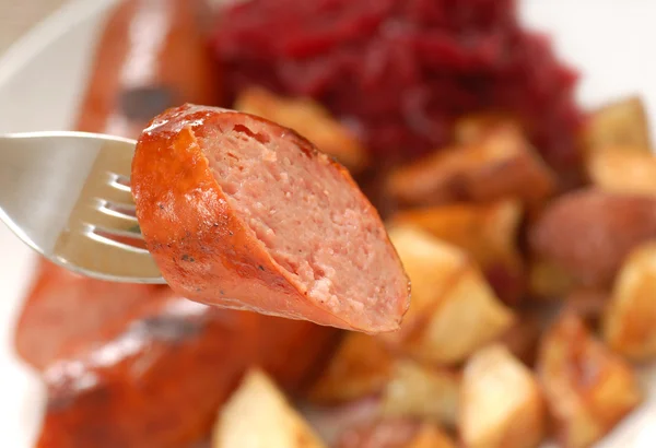Piece of smoked sausage on a fork — Stock Photo, Image