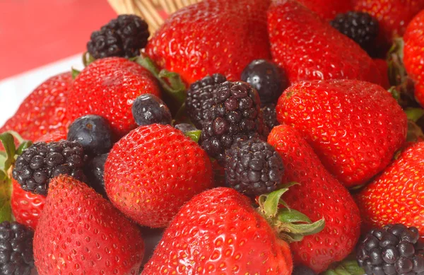 Fresas frescas, moras y arándanos que se derraman — Foto de Stock