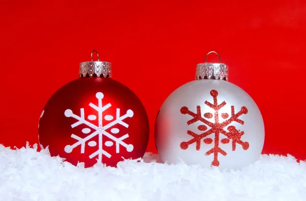 Два рождественских украшения в снегу — стоковое фото
