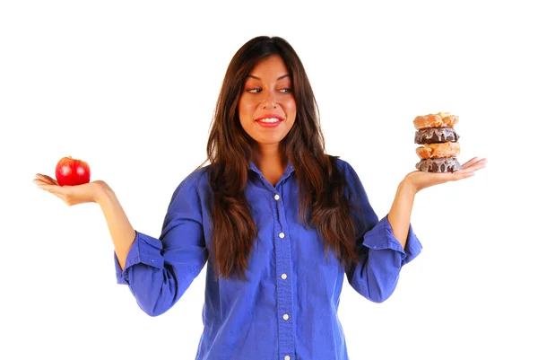 Attraktiv kvinna beslutar att äta äpple eller donut Stockbild