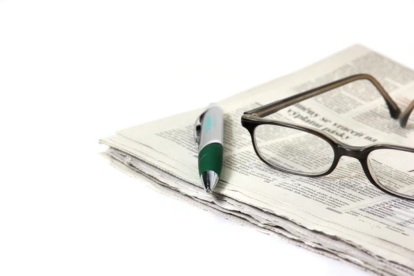 Caneta e óculos em jornal — Fotografia de Stock