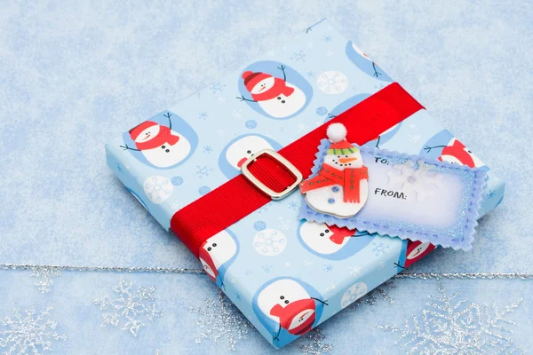 Um presente de Natal com uma etiqueta de presente em branco em um backgro floco de neve — Fotografia de Stock
