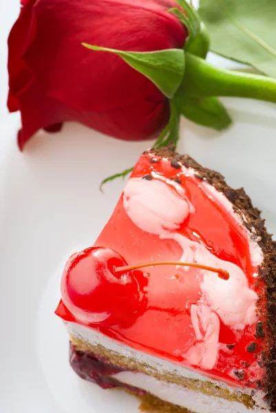 Un trozo de pastel y una rosa roja — Foto de Stock