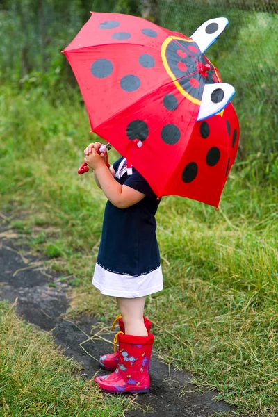 Het kleine meisje, paraplu en rubber laarzen Stockfoto