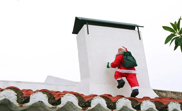 Jultomten klättrar i skorstenen Stockbild