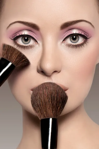 Retrato de uma mulher bonita com uma escova de maquiagem — Fotografia de Stock