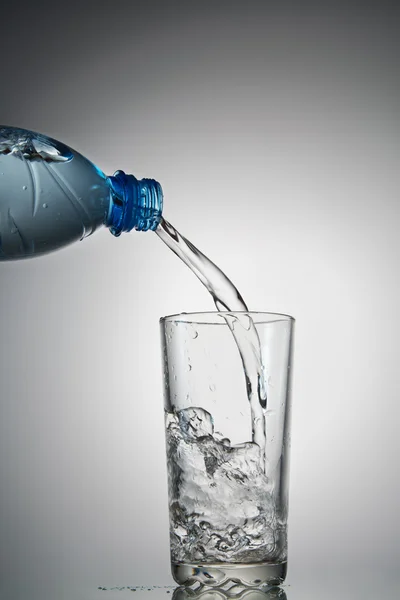 A água flui em um copo — Fotografia de Stock