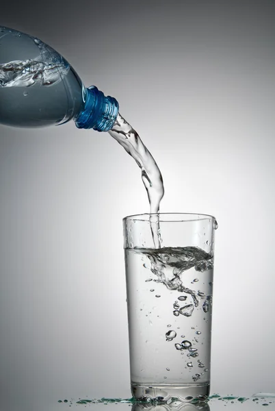 A água flui em um copo — Fotografia de Stock