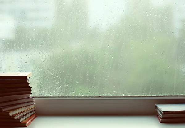 stock image Pile of books before a window