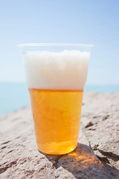 Пластиковый стакан пива на скале — стоковое фото