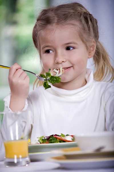 집에서 샐러드를 먹는 어린 소녀. 스튜디오 촬영 — 스톡 사진