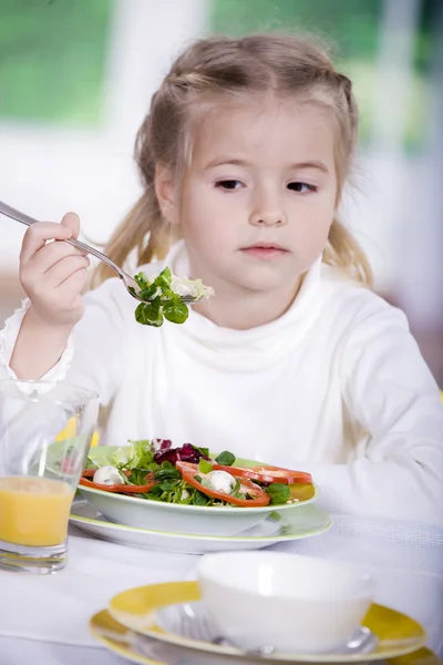Giovane ragazza che mangia insalata a casa. Un servizio in studio Fotografia Stock