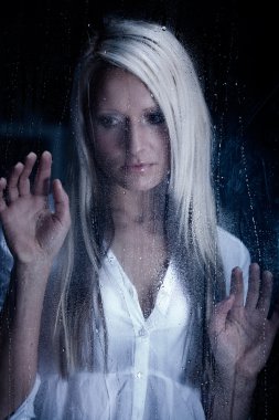Yağmurlu bir pencerenin arkasındaki kadın