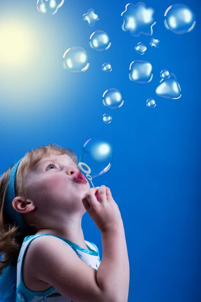 Egy kislány szappanbuborékokat fúj. — Stock Fotó