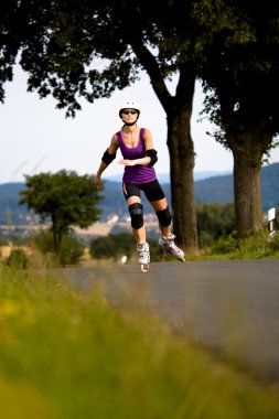 Young woman on rollerblades in the country clipart