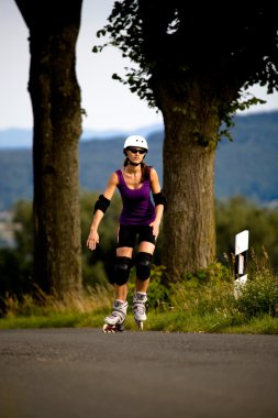 Young woman on rollerblades in the country clipart