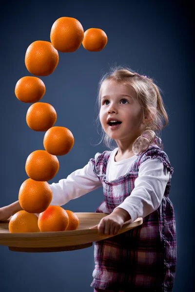 Girl balancing oranges — Stock Photo, Image