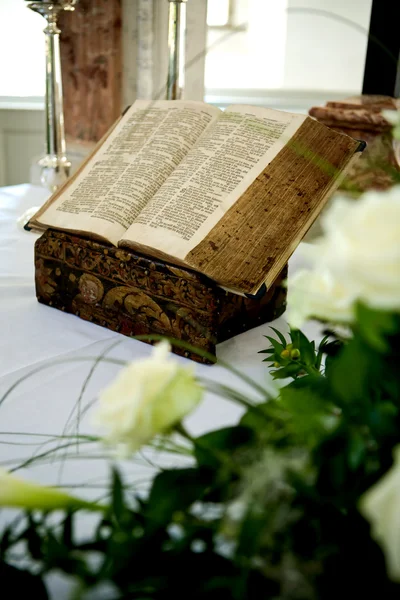 Heilige Bijbel en bloemen op altaar in de kerk — Stockfoto