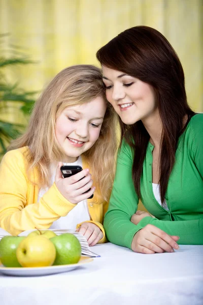 Två tjejer med en mobiltelefon — Stockfoto